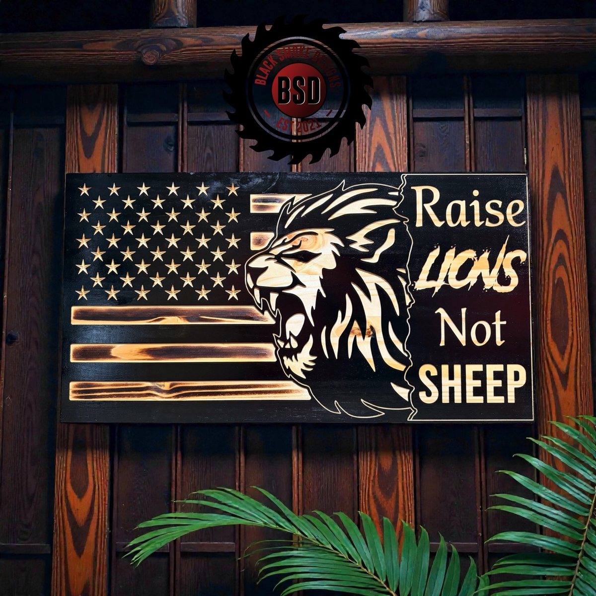 Black carved flag with a lion and Raise Lions Not Sheep text