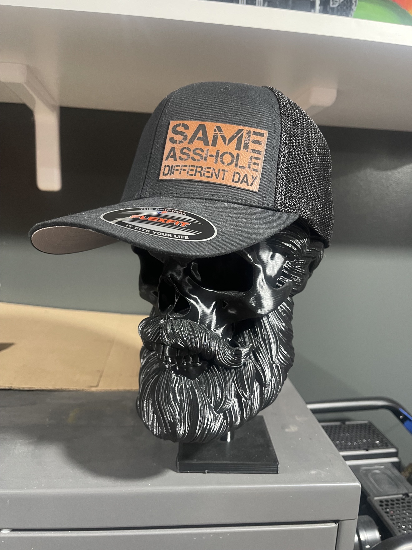 Grey hat with an engraved leather patch displayed on a black bearded skull